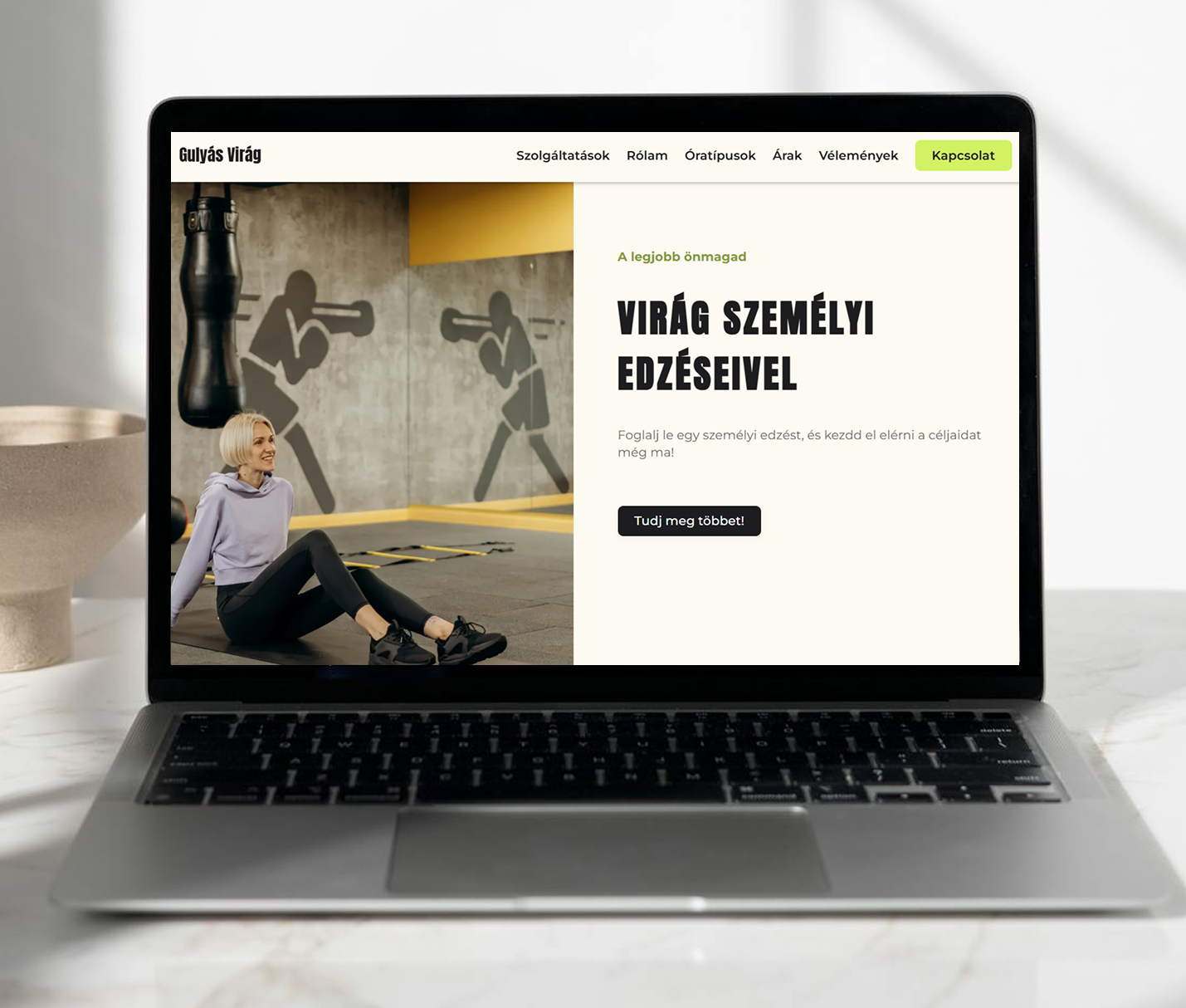 Laptop screen showing a fitness website with a woman sitting on gym floor and text offering personal training sessions.